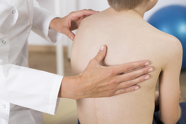 boy with scoliosis being examined by orthopedic spine surgeon dr. javier reto